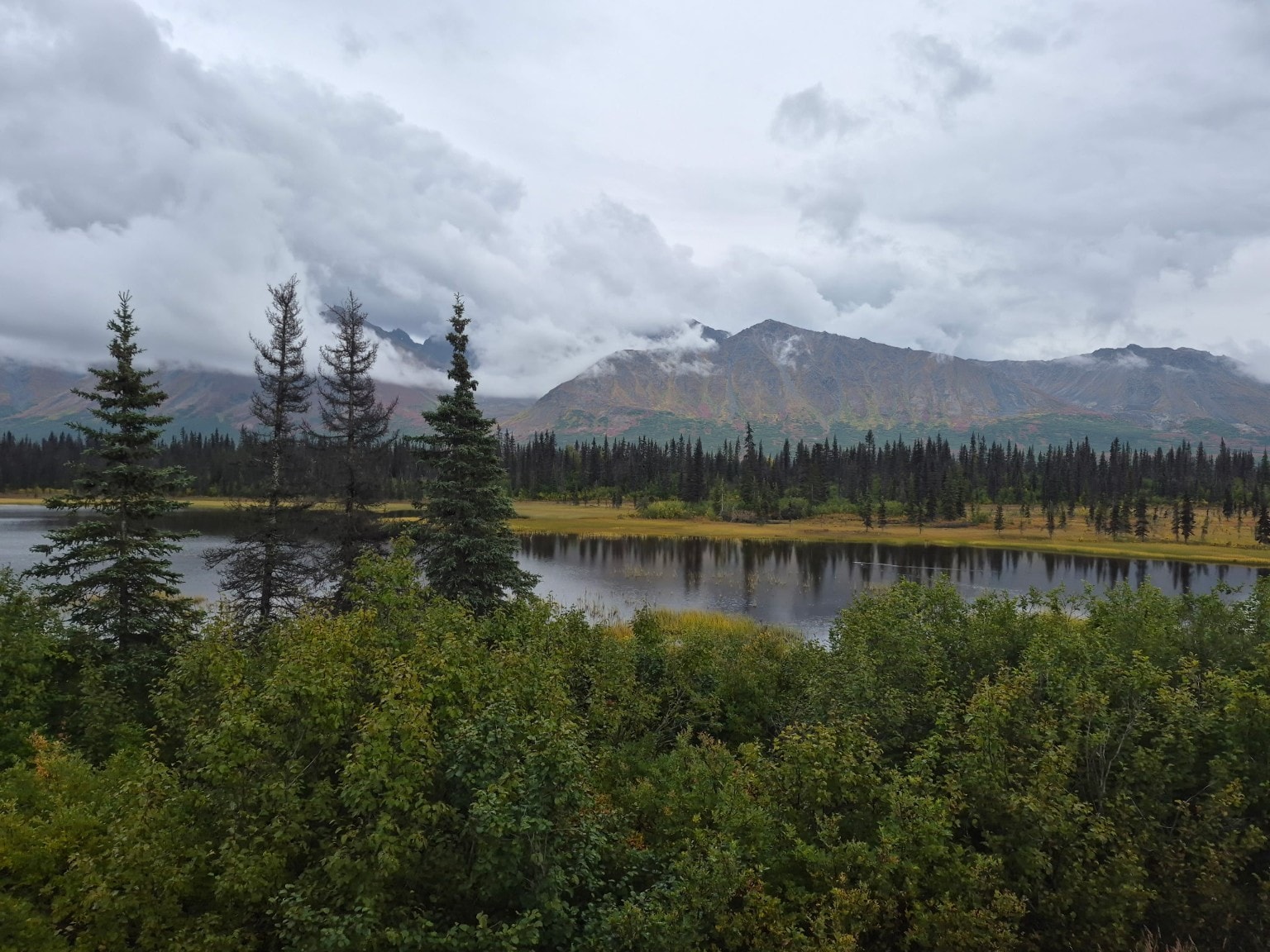 Alaska mountain and lake landscape with evergreen forest and autumn colors
